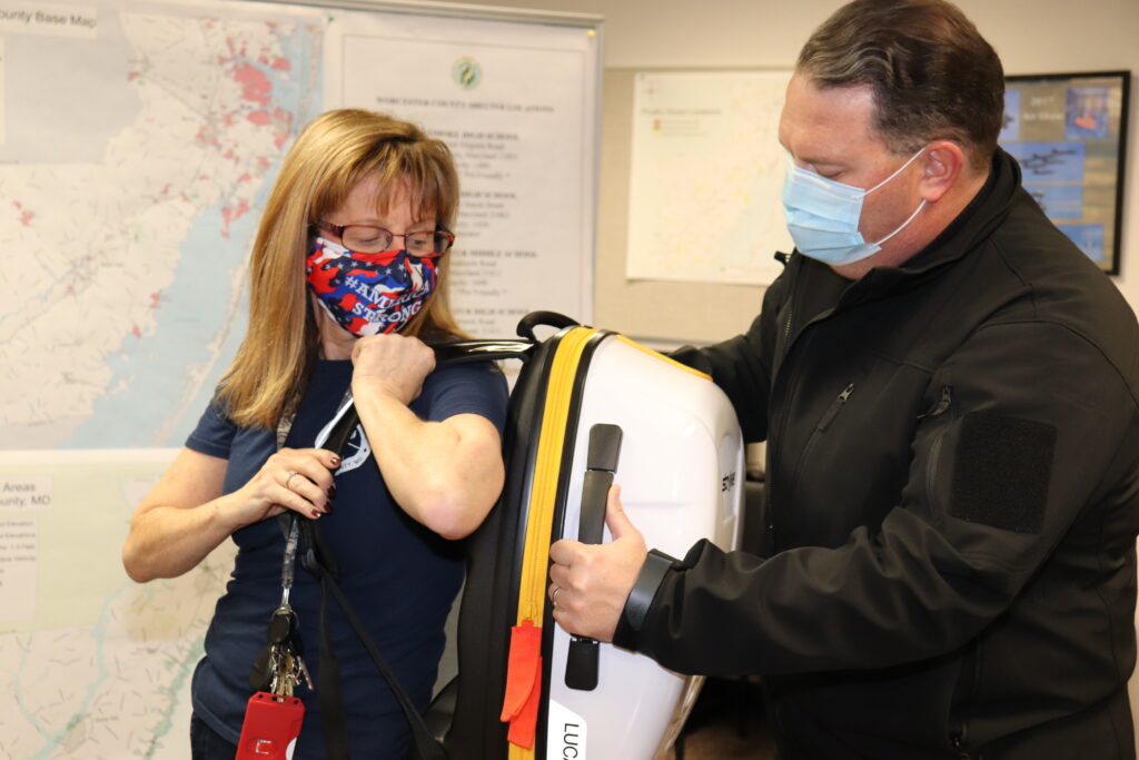 Worcester County Emergency Services (WCES) Planner Laraine Buck (left) and Director Billy Birch demonstrate the portability of a LUCAS hands-free mechanical CPR devise. WCES utilized approximately $168,000 in CARES Act funds to purchase nine LUCAS units for nine volunteer fire companies in Worcester County and to reimburse another volunteer fire company for the cost of one unit purchased independently.
