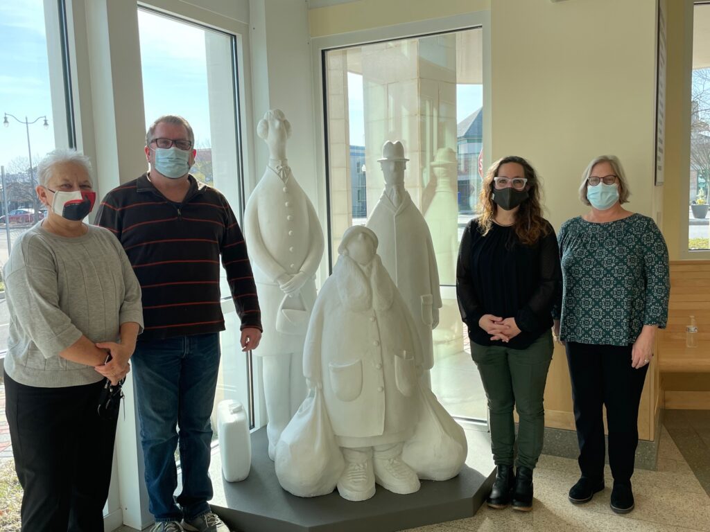 From left, Rehoboth Beach City Manager Sharon Lynn, RAL Exhibitions Coordinator Nick Serratore, RAL Executive Director Sara Ganter, and RAL Choptank Collections Manager Melissa May stand around the sculpture “Bus Stop.” They attended the installation of the sculpture in the atrium at City Hall.