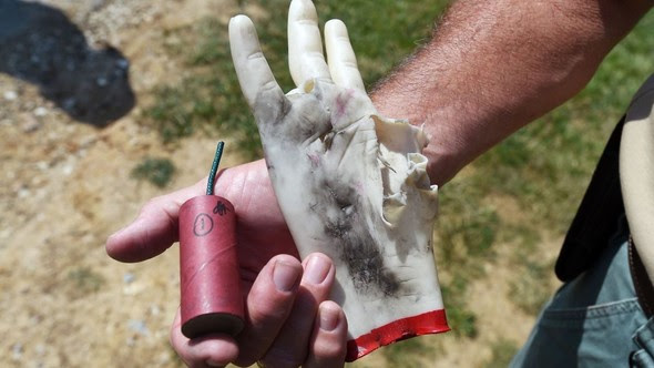 Maryland State Fire Marshal bomb squad member shows the aftermath of a rubber hand that held a quarter stick illegal firework, left, to show the danger of using illegal fireworks