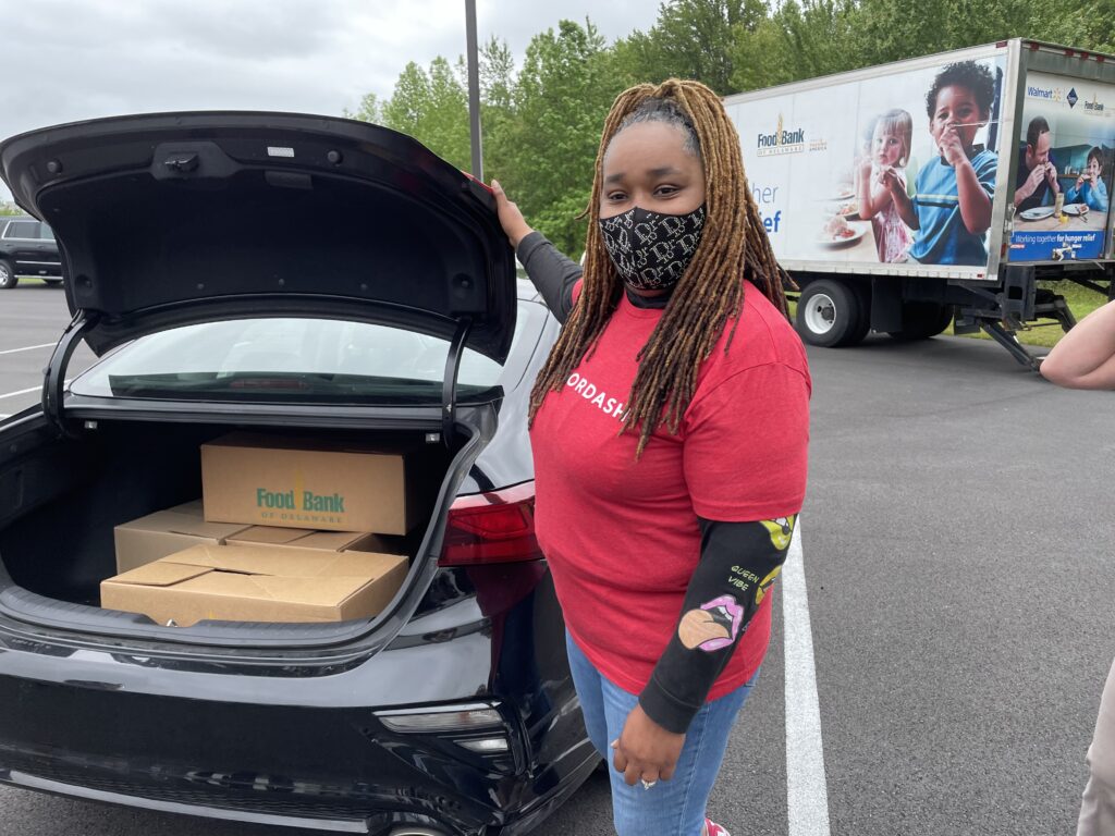 DoorDasher Lydia Conway poses next to her vehicle that’s been loaded with the first DoorDash delivery from the Food Bank of Delaware