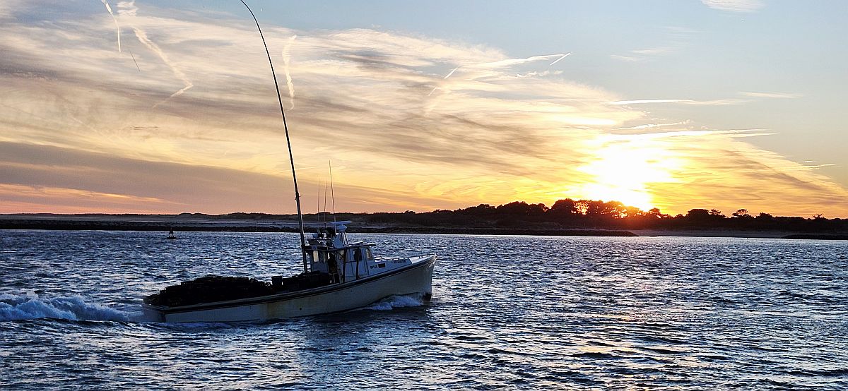 A fishing boat returns through the Ocean City Inlet at sunset.