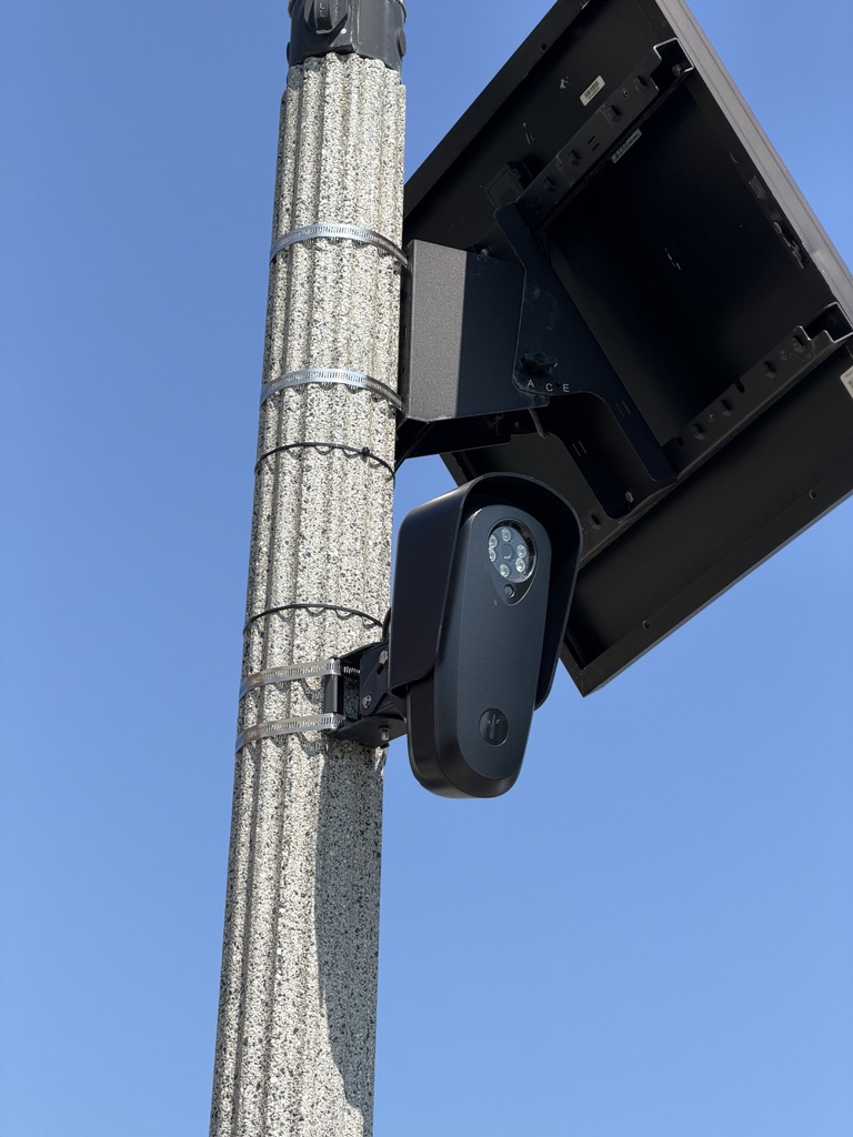 A publicly acknowledged automated license-plate reader and its solar panel mounted on a roadside pole near the Rehoboth Avenue canal bridge.