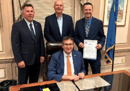 L-R:  Director of Communications Director Eric Wagner, 911 Emergency Services Board member Michael Vincent, E911 Director Robert Williams, and Governor Matthew Meyer (center) / Image courtesy DSHS