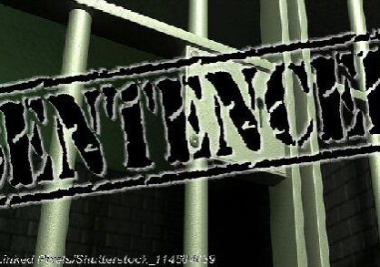 A closeup of the lock of a brick jail cell with iron bars and a door with a locking mechanism - Photo: © Copyright Linked Pixels/Shutterstock