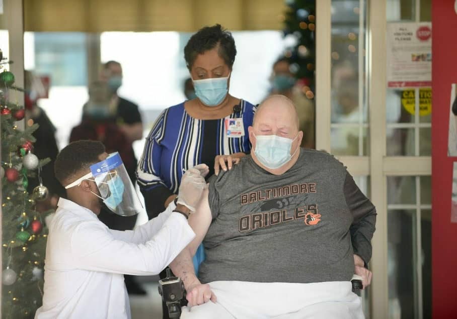 The first Maryland nursing home resident to receive the vaccine was Samuel Cushing. He is accompanied by Donna Jones, Director of Nursing, who was among the first staff members to be vaccinated.