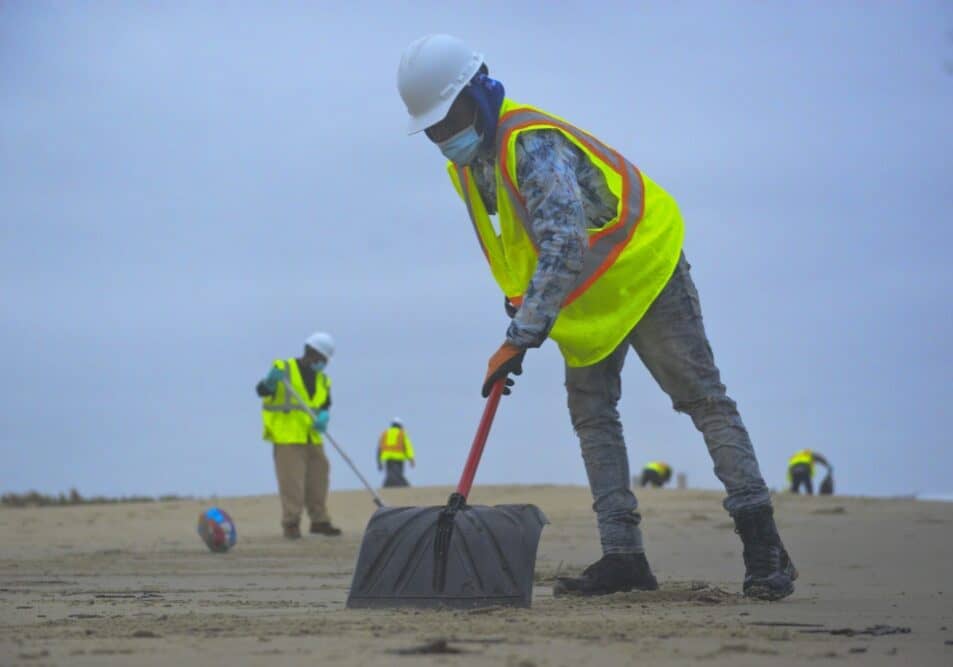 A member of a contracted oil spill response organization cleans oily debris from Slaughter Beach in Delaware as part of the Broadkill 2020 oil spill response, Oct. 25, 2020. The Coast Guard and the Delaware Department of Natural Resources and Environmental Control are working together to identify areas where tar balls and oily debris are making landfall to facilitate an effective clean up.(U.S. Coast Guard photo by Petty Officer 3rd Class Isaac Cross.)