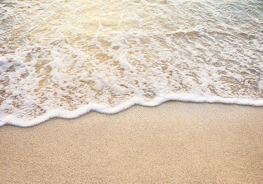 Picutre of wave rolling up beach with sea foam