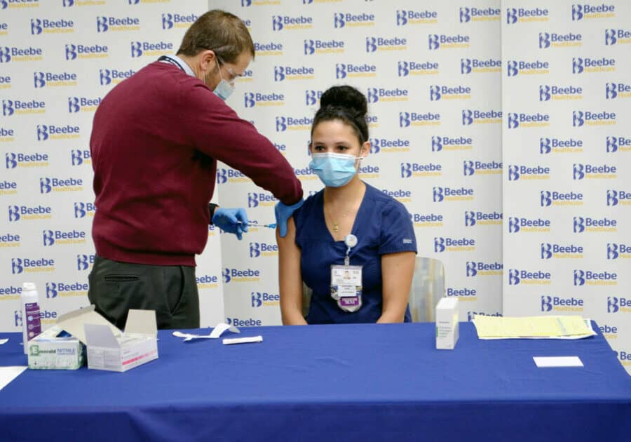 Sintia Rodriguez, RN, who works in Beebe’s Emergency Department and behavioral health unit, receives the first vaccination in Sussex County from Dr. Bill Chasanov, at the Margaret H. Rollins Lewes Campus. Photo courtesy of Beebe Healthcare.