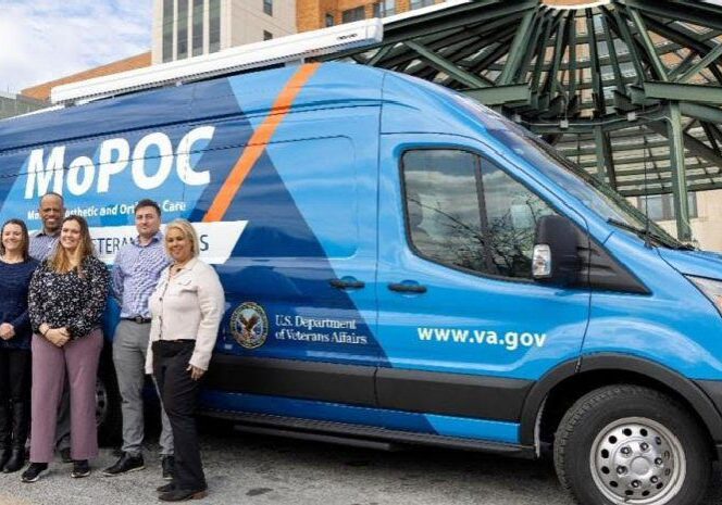 L-R - Prosthetics Chief Corey Smith, Advanced Medical Support Assistant Rosemarie Hawkins, Prosthetic Representative Tina Parsons, Prosthetic Assistant Chief Warren Lingham, Certified Prosthetist and Orthotist Cassandra Thatcher, Certified Pedorthist Devin Burgin, and Inventory Manager Mayra Hurtado standing next to the Mobile Prosthetic and Orthotic Mobile Clinic in front of the Wilmington VA Medical Center